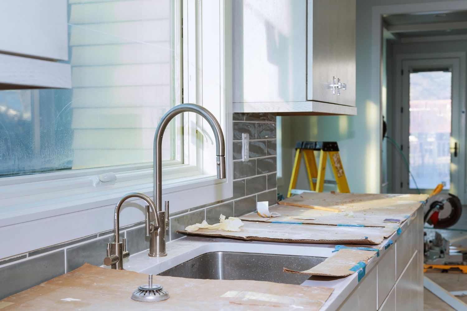 A kitchen under construction with a sink and a window.