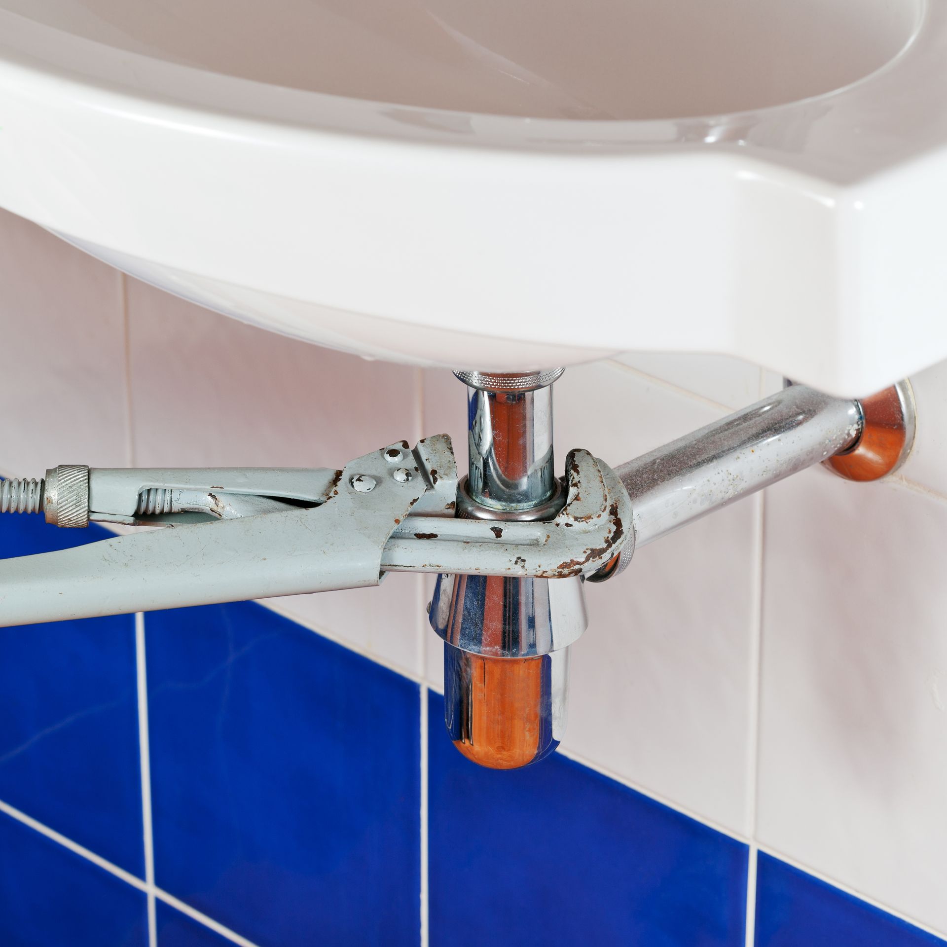 A bathroom sink with a wrench attached to it