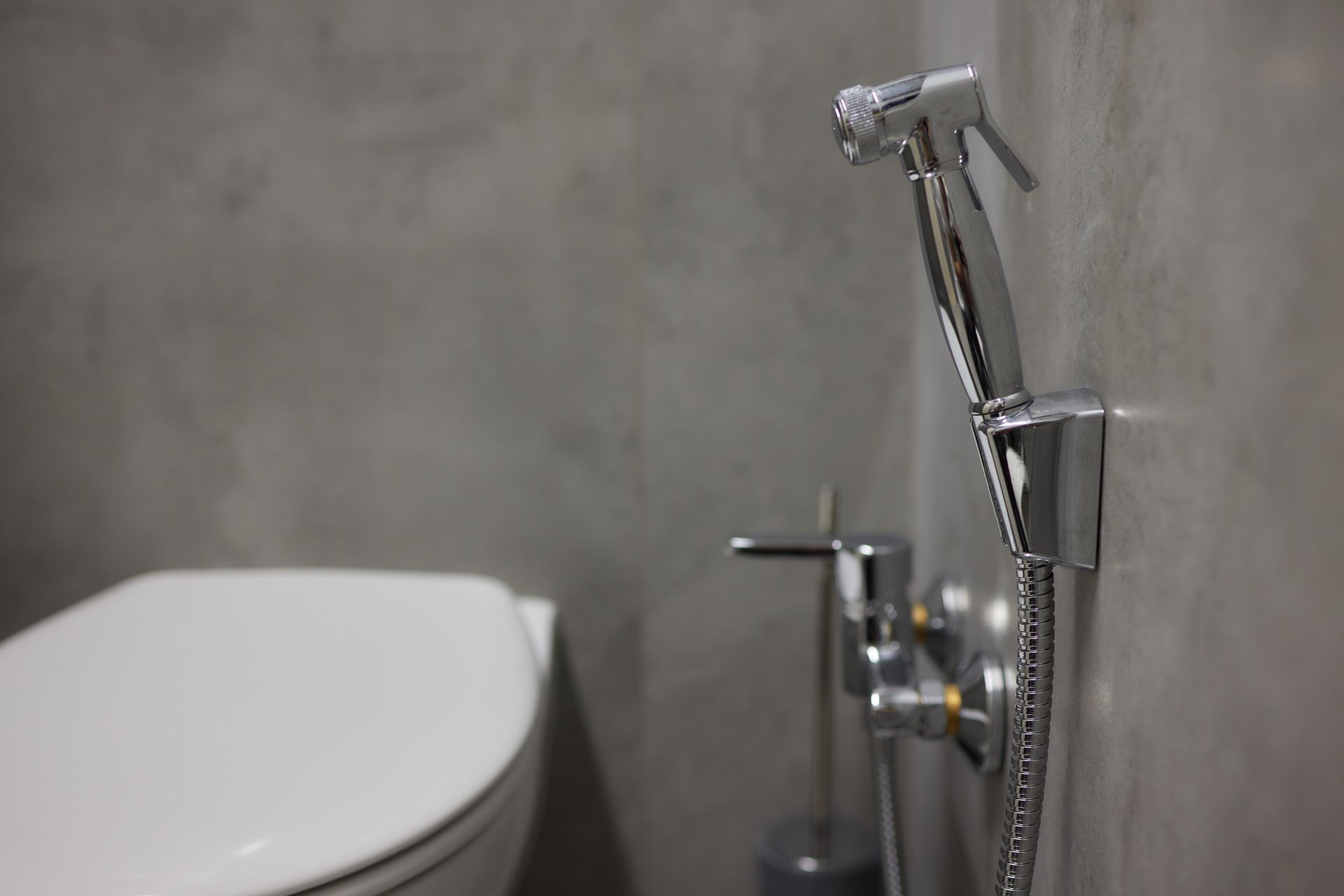 A man is fixing a shower head in a bathroom.