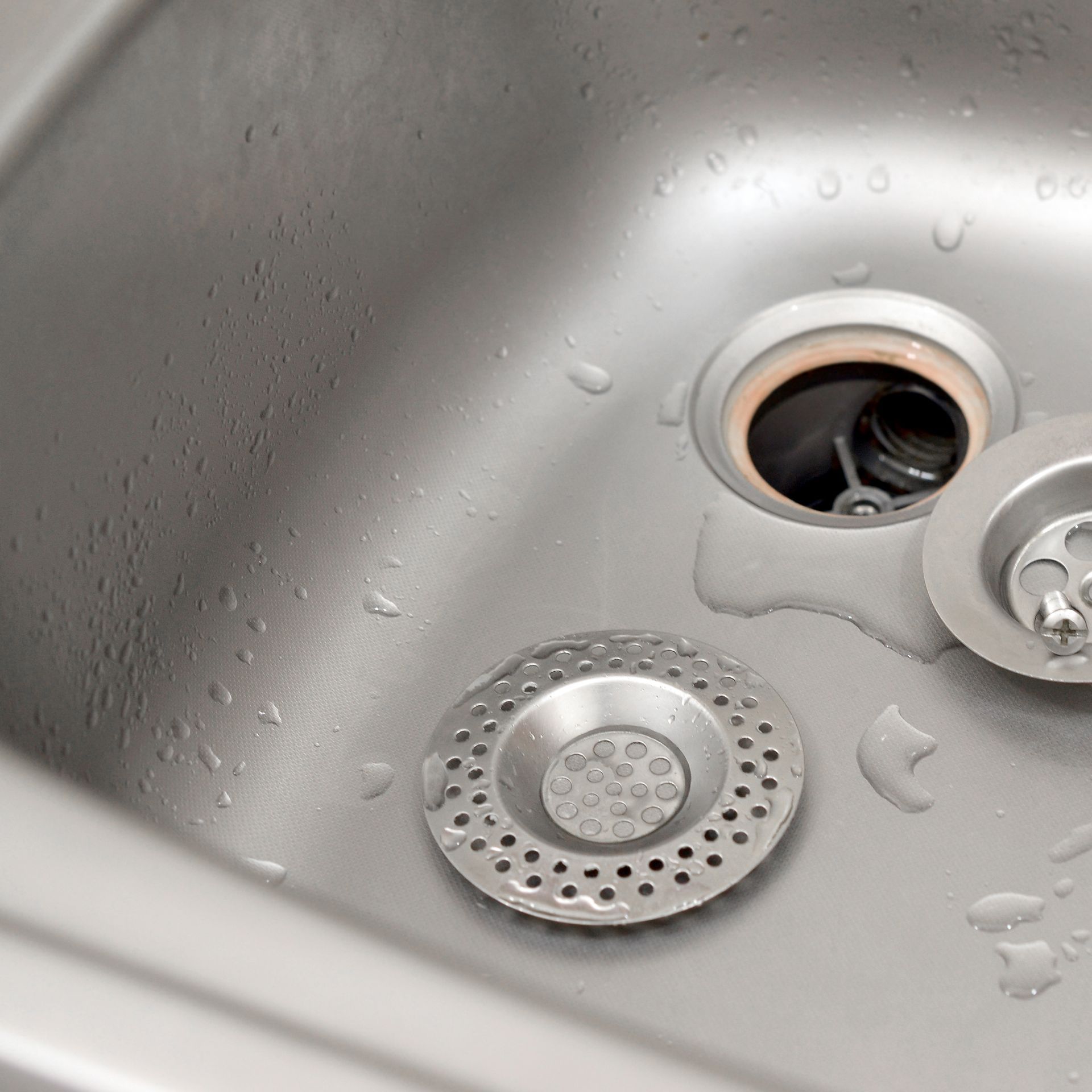 A close up of a stainless steel kitchen sink with a drain.