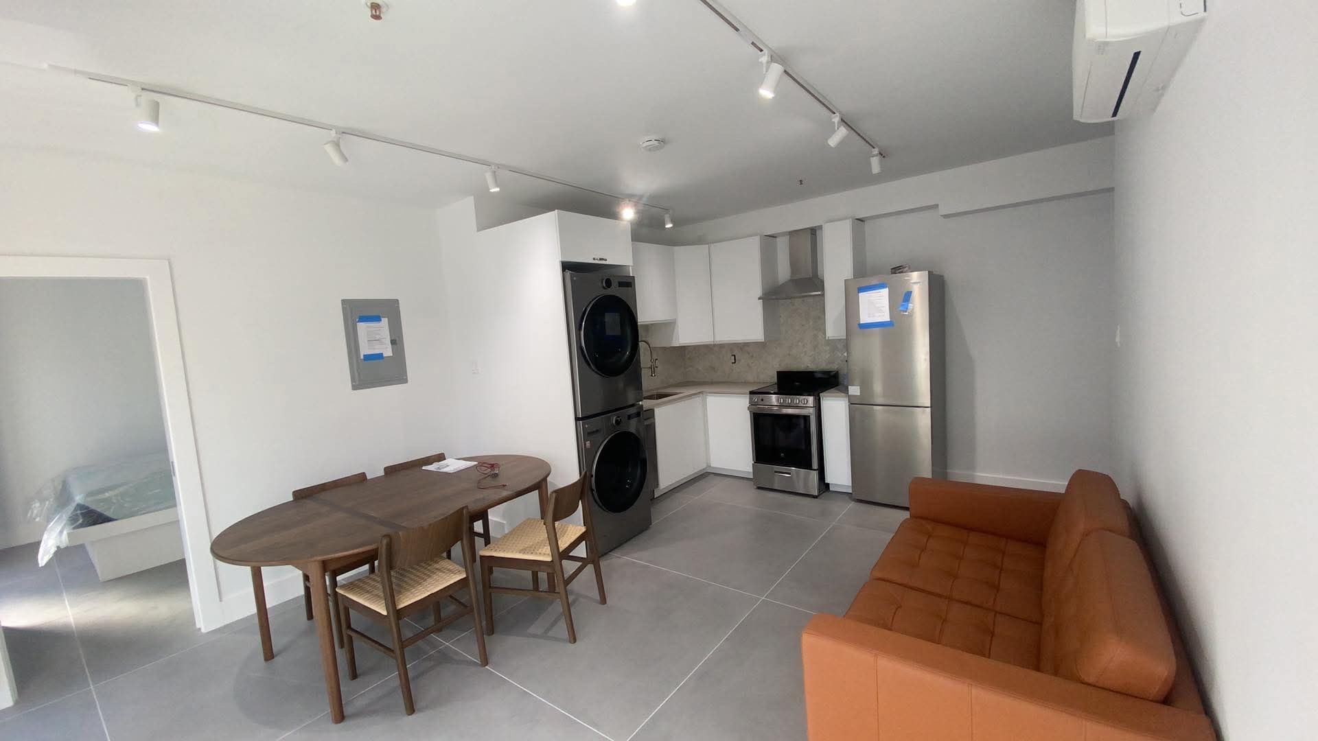 A living room with a couch , table , chairs and a refrigerator.