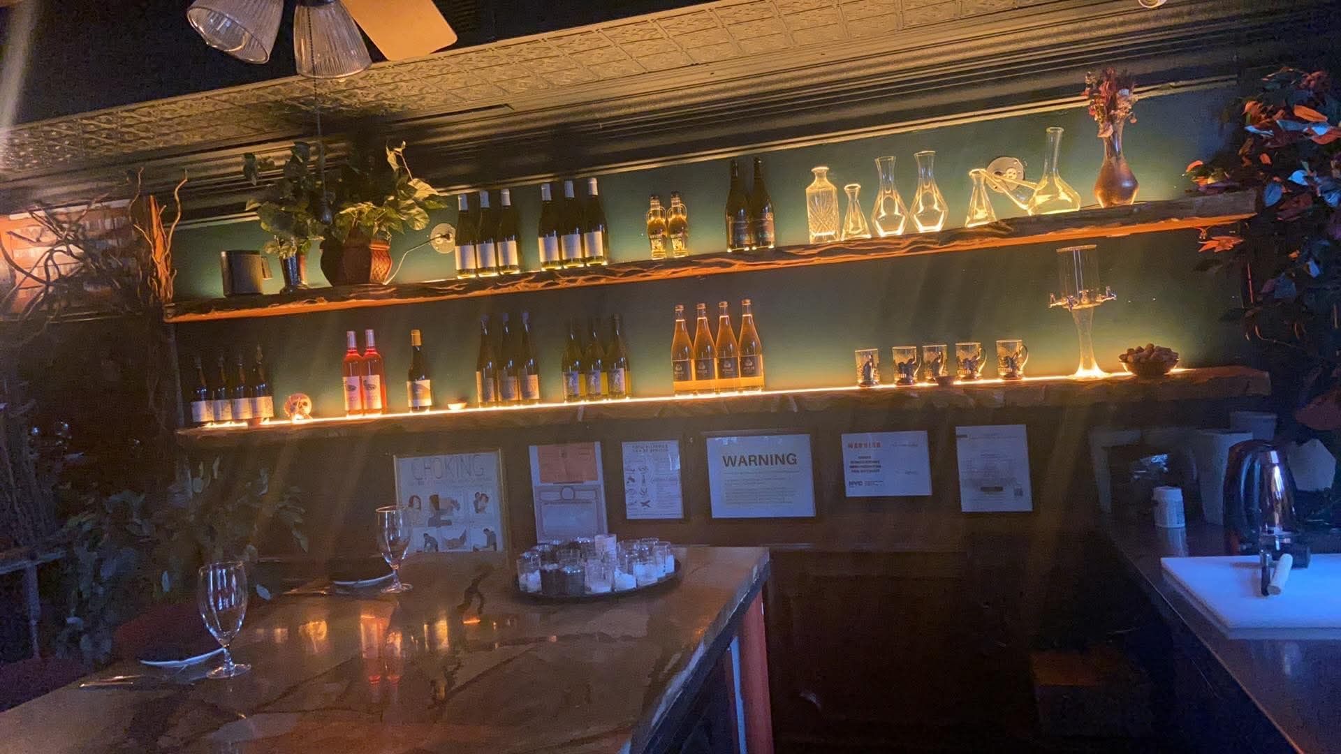 A bar with a lot of bottles and glasses on the shelves