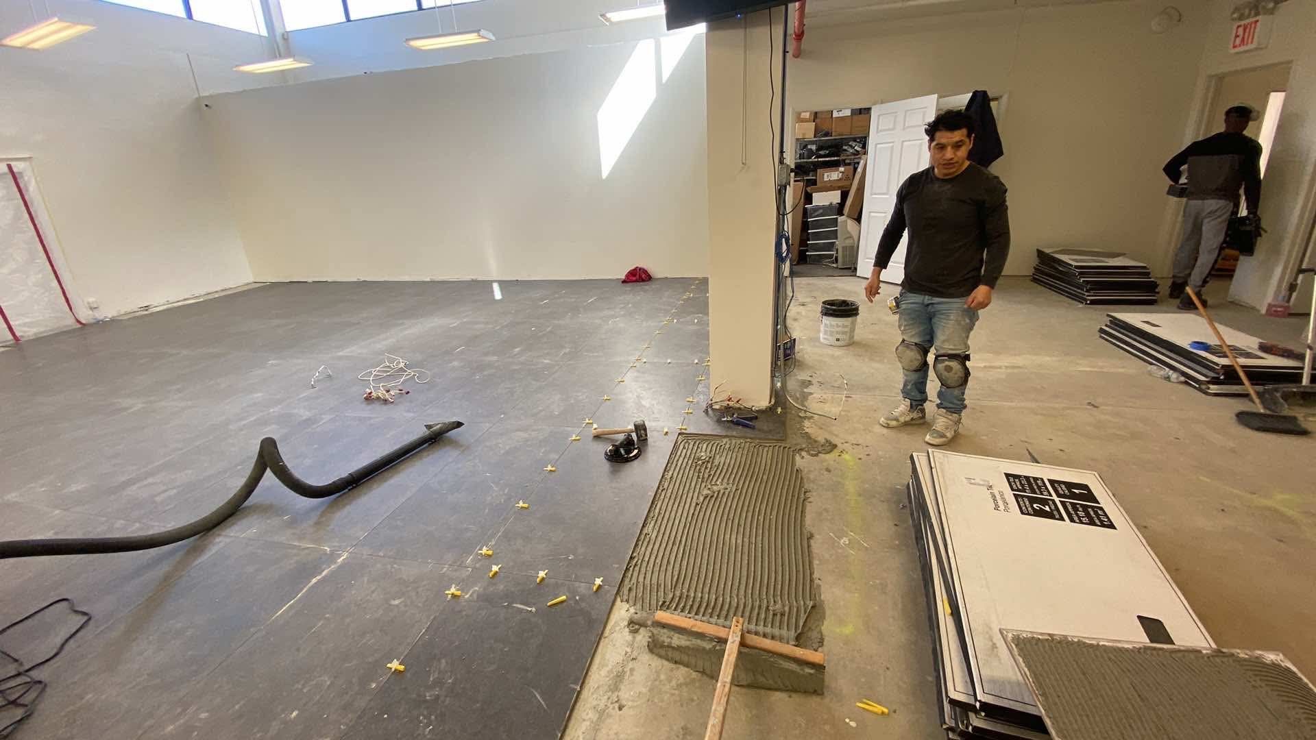 A man is standing in a room with tiles on the floor.