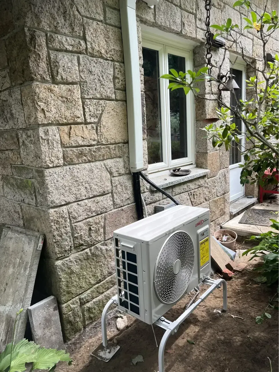 Exterior of stone building with white air conditioning unit on metal stand.