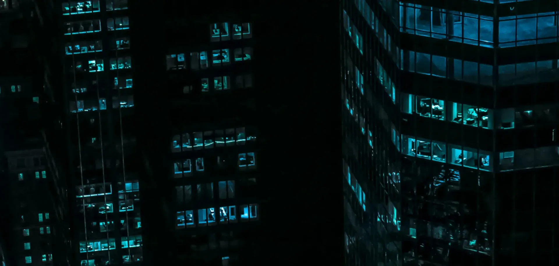 A group of tall buildings are lit up at night.