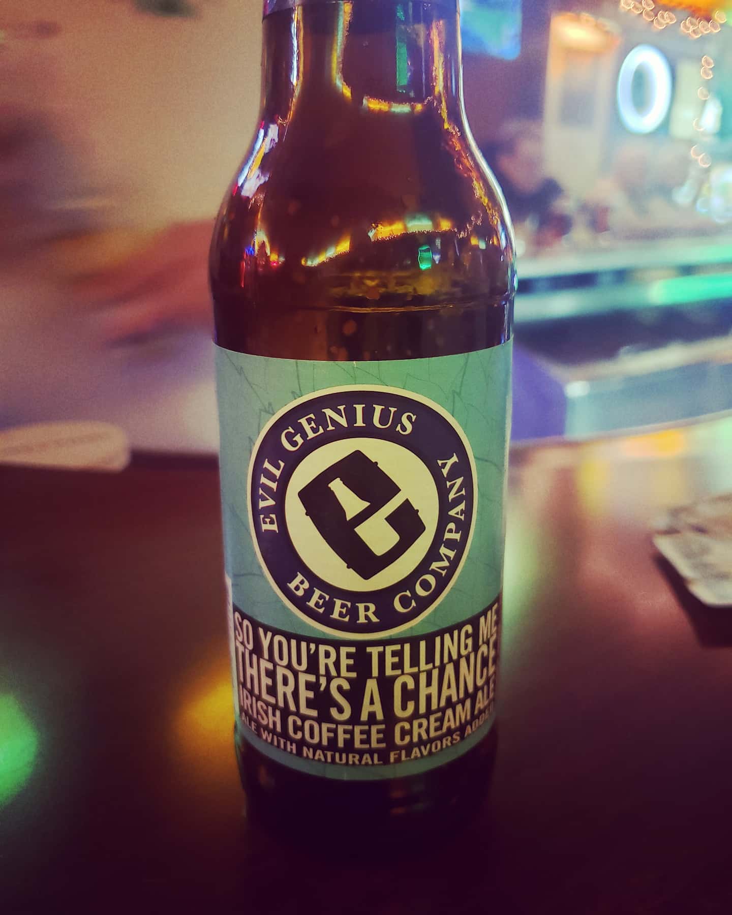 A bottle of evil genius beer company sits on a bar
