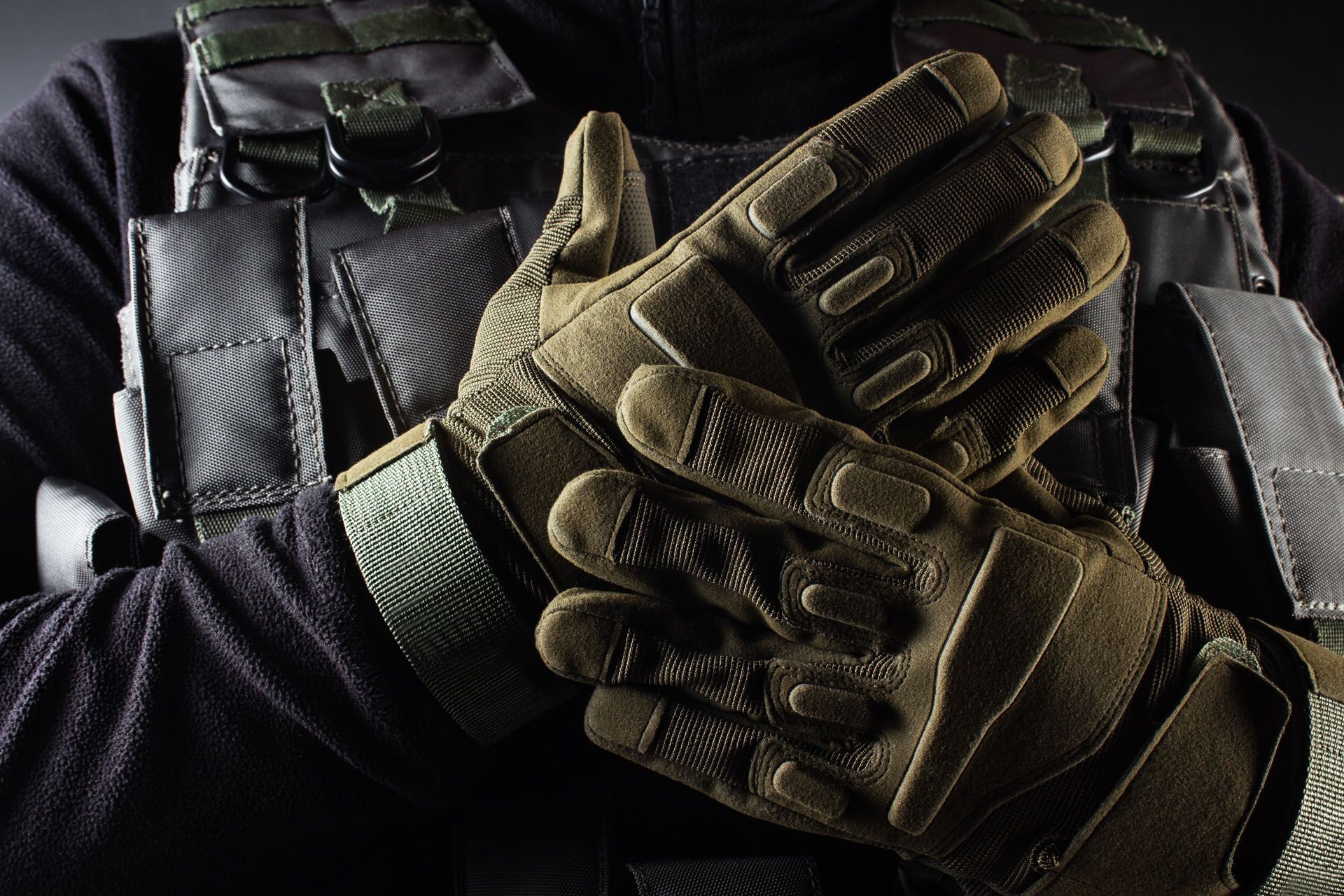 A close up of a person wearing tactical gloves.