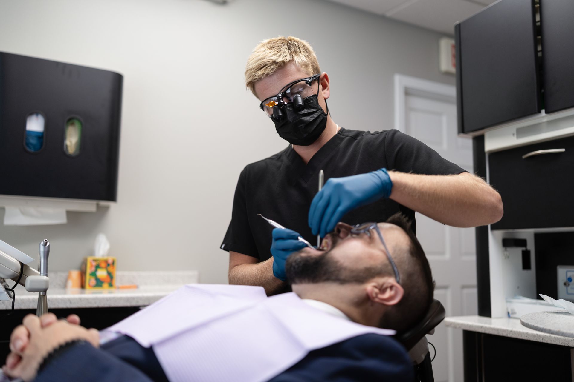 Male dentist working on middle aged male patient lying in chair
