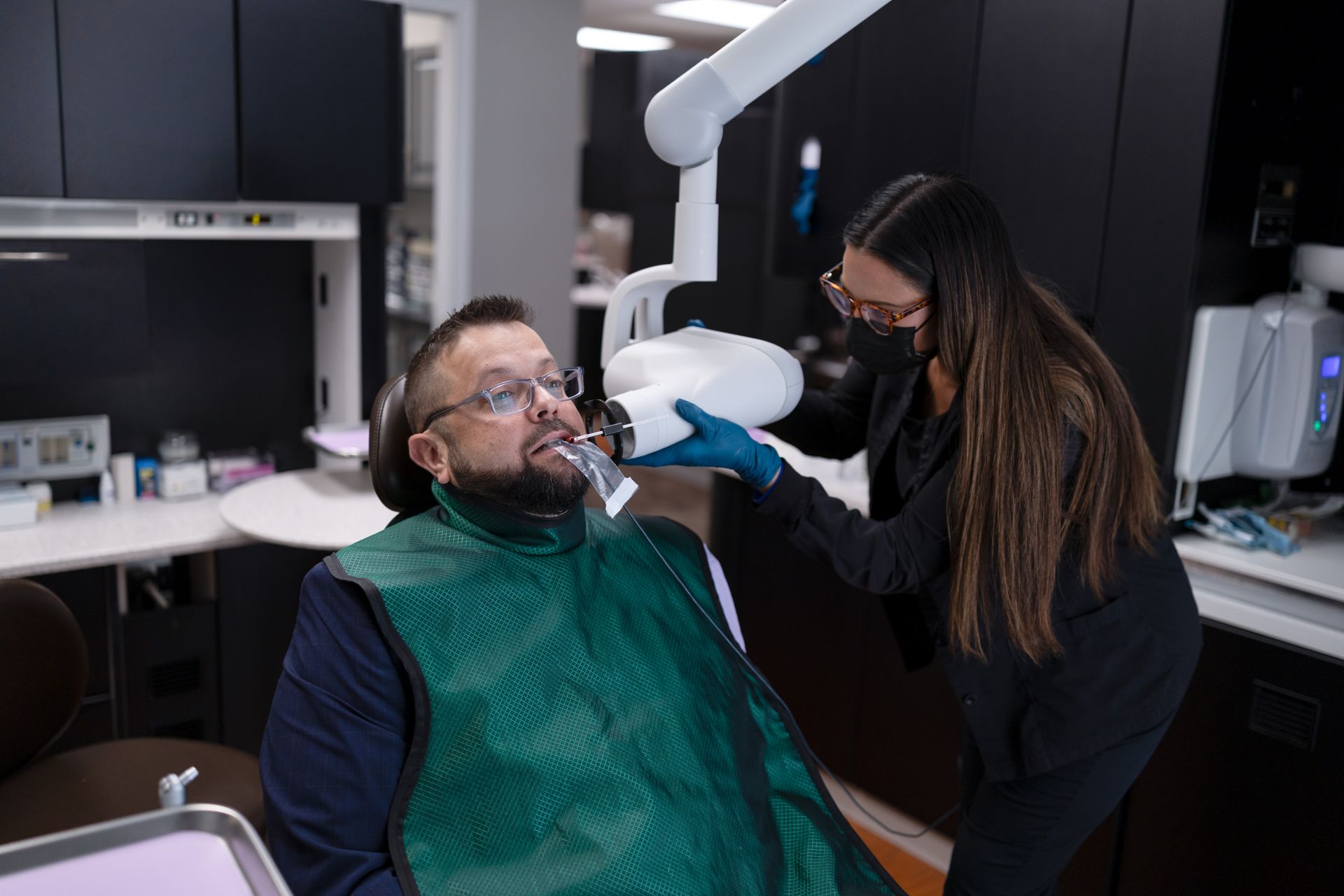 Patient sitting in a dental chair getting x-rayed by a dental hygienist