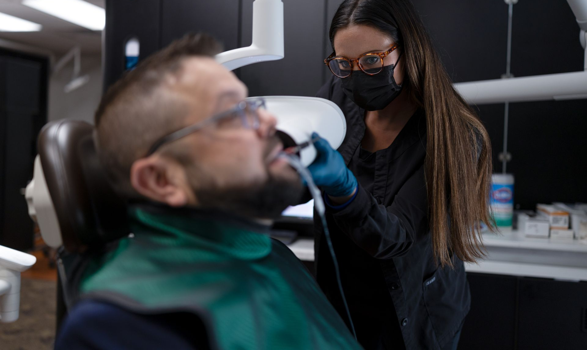 Dental assistant holding an x-ray scanner to a patients mouth 