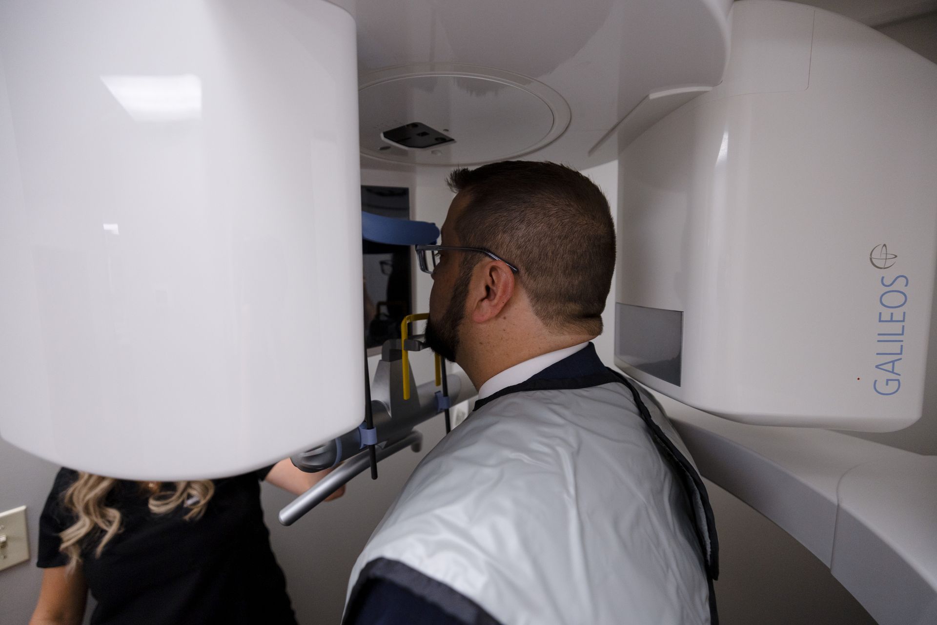 Male dental patient standing in an xray machine wearing protective gear