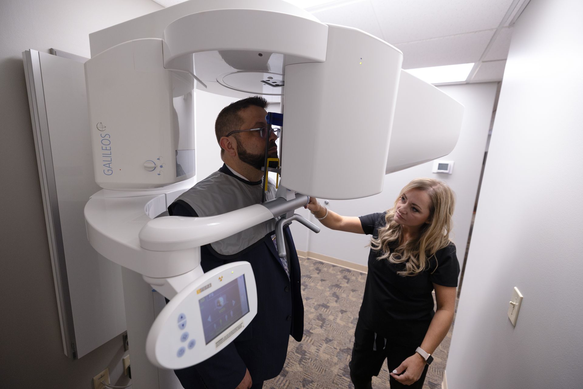 Man standing in an x-ray machine controlled by a dental assistant