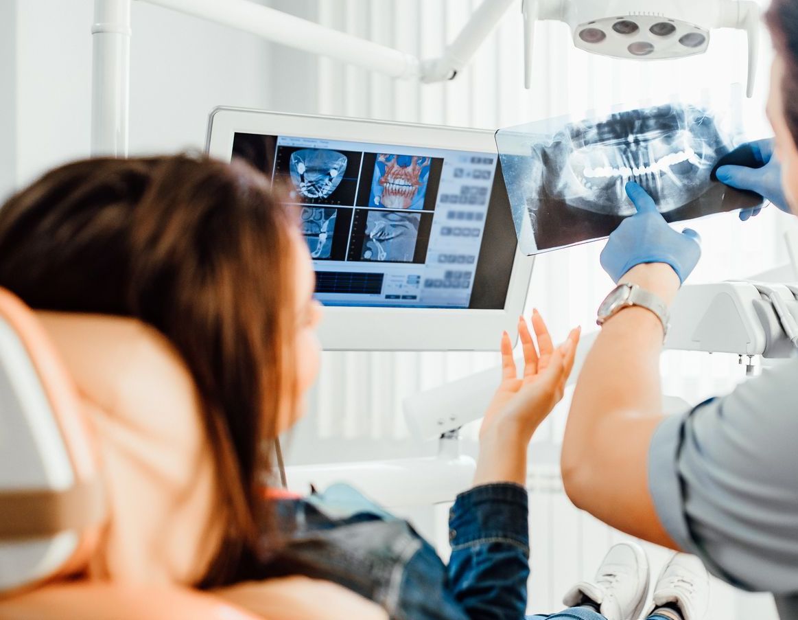 A dentist is looking at an x-ray of a patient 's teeth.