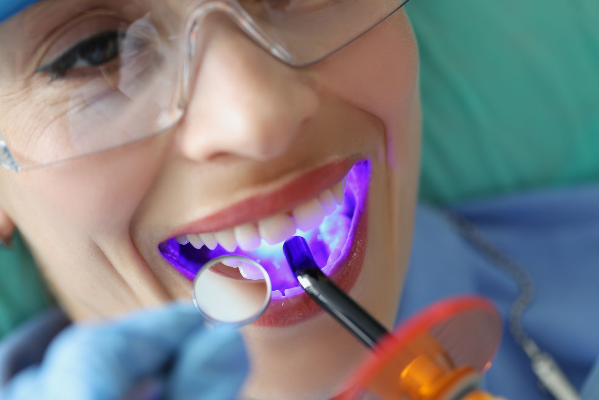 A woman is getting her teeth whitened by a dentist.