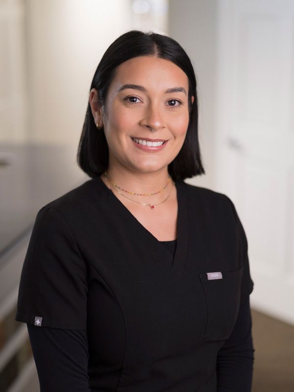 A woman with short hair smiling at camera in black scrubs