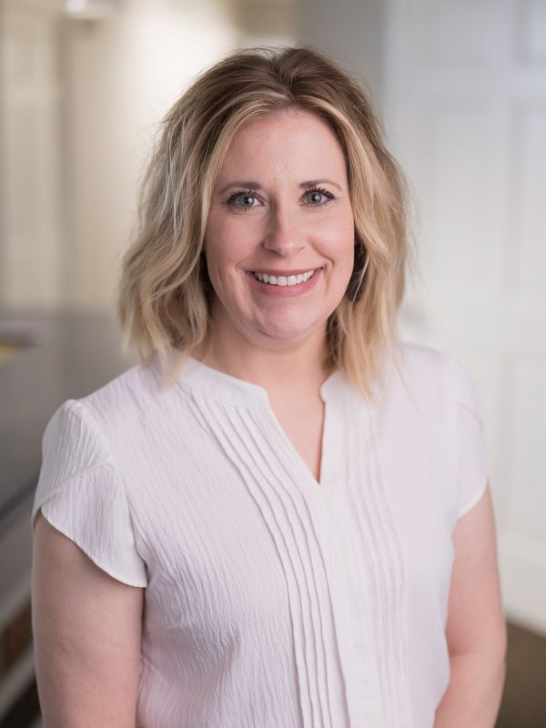 Blonde hair receptionist wearing a white blouse smiling for camera