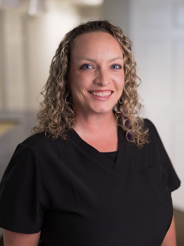 A woman with curly hair smiling at the camera in a dentist office