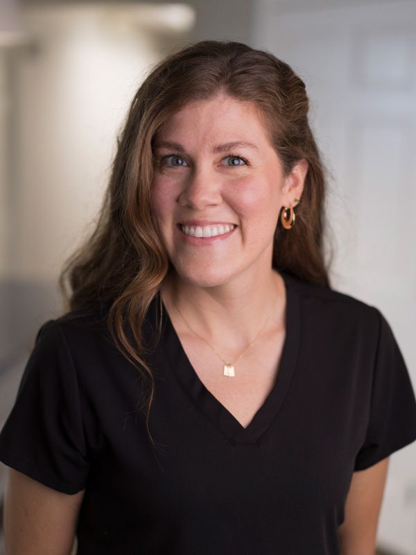 Woman in dentist office wearing black top smiling at camera
