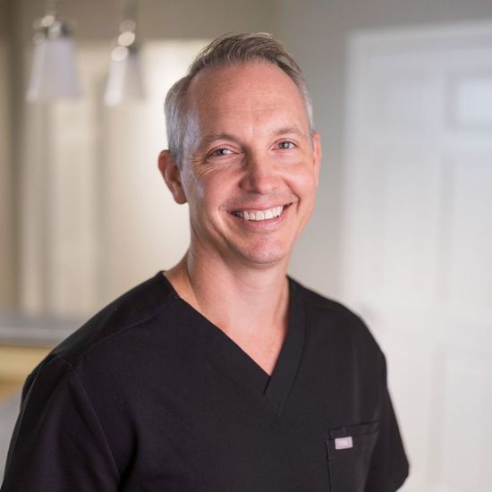 Geoffrey Riley in a black shirt is smiling for the camera