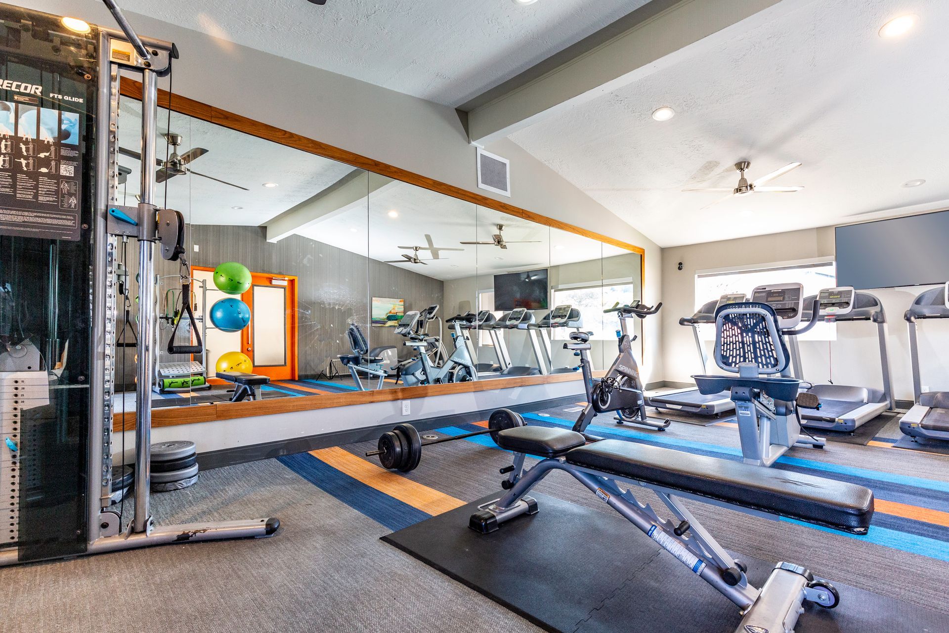 a large gym with a lot of equipment and a large mirror .