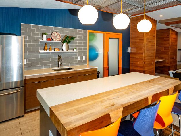 a kitchen with a large wooden table and colorful chairs