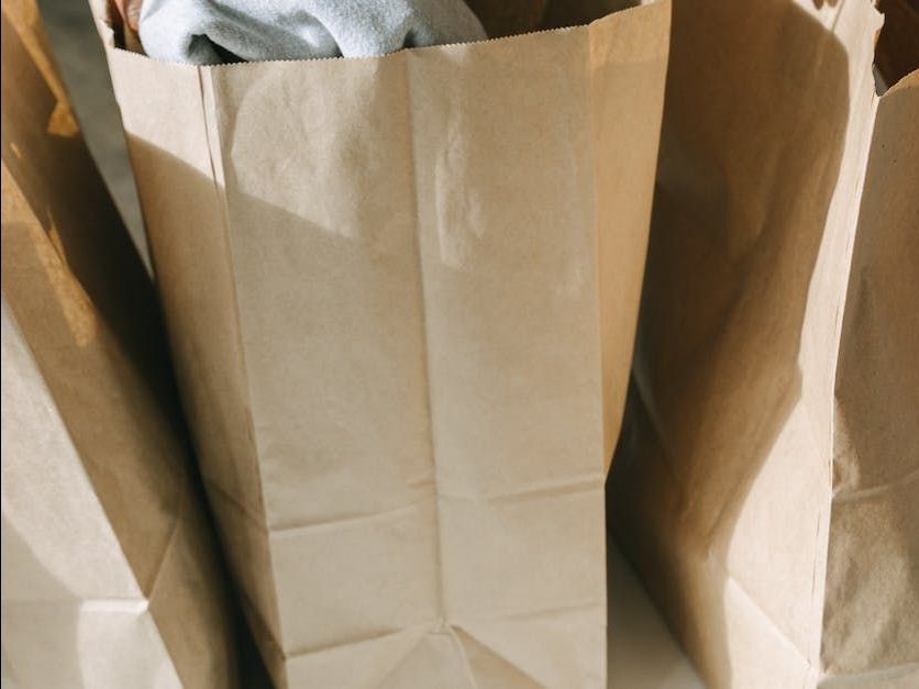 three brown paper bags filled with clothes are sitting on a table .