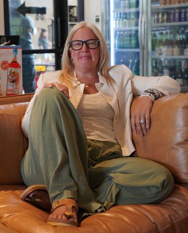 A woman wearing glasses is sitting on a couch with her legs crossed.