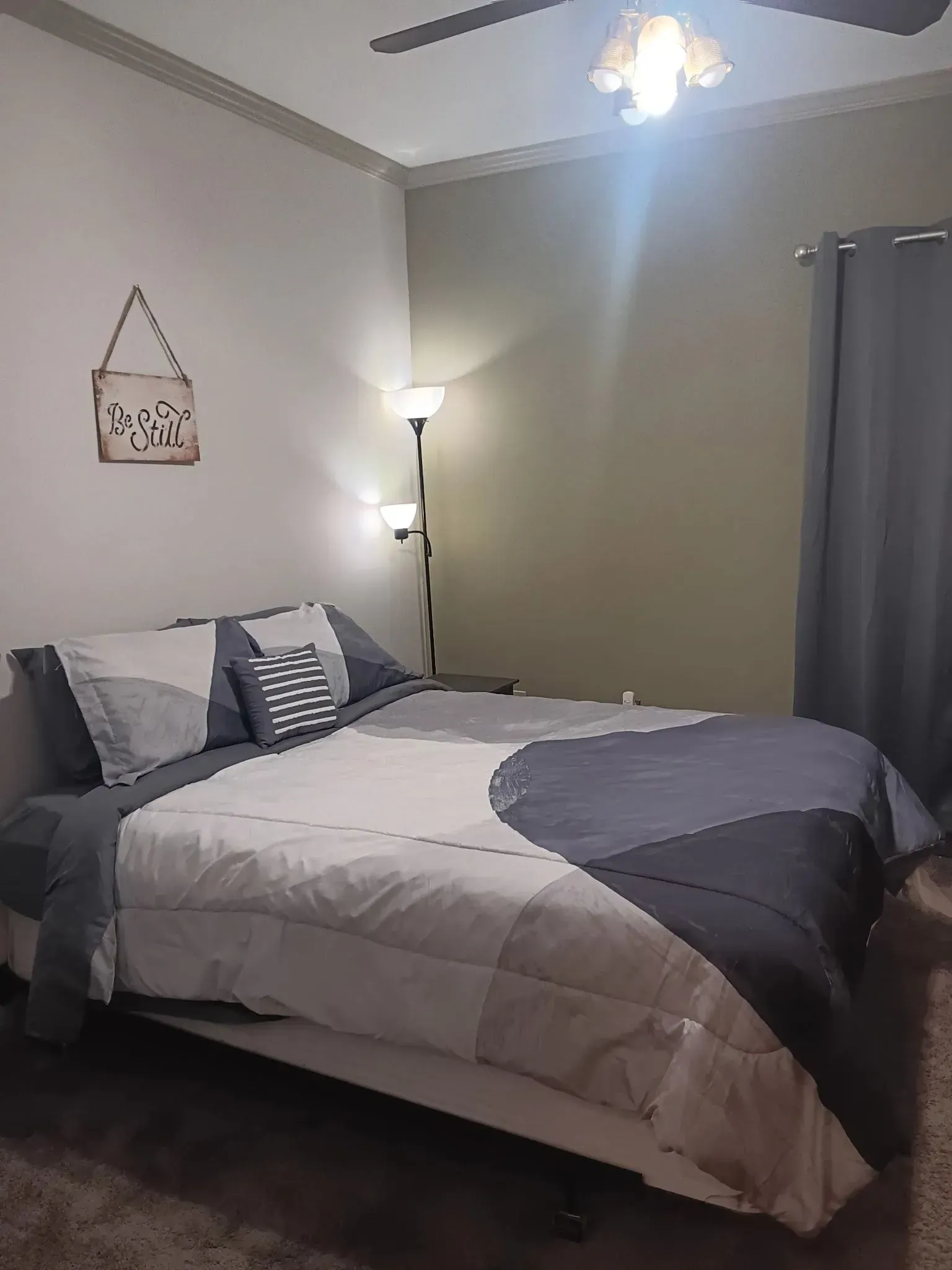 A bedroom with a bed , lamp , and ceiling fan.