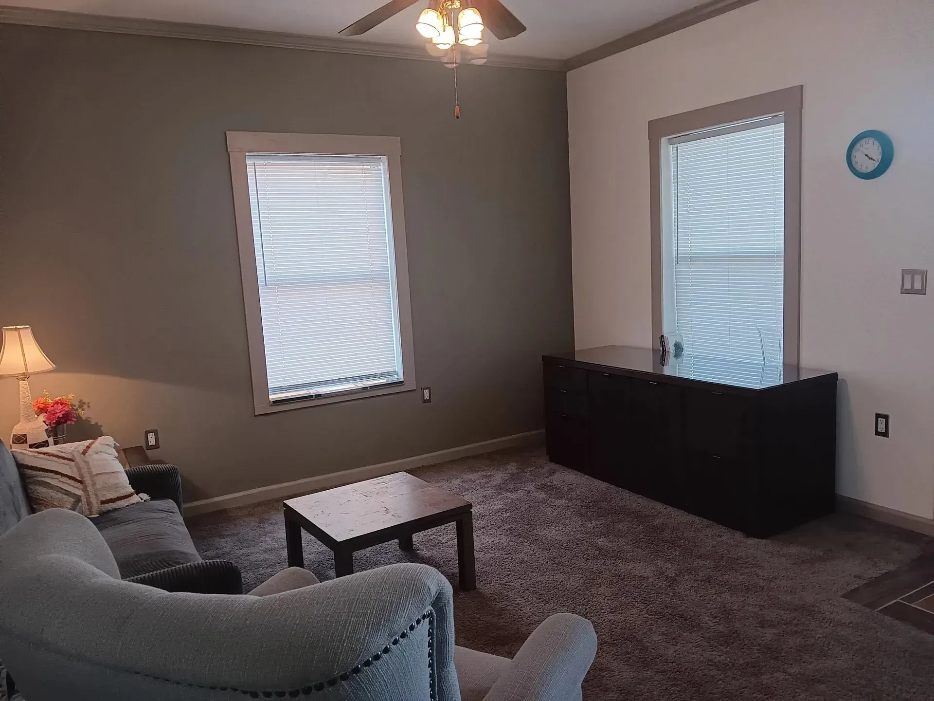 A living room with a couch , chair , table and a ceiling fan.