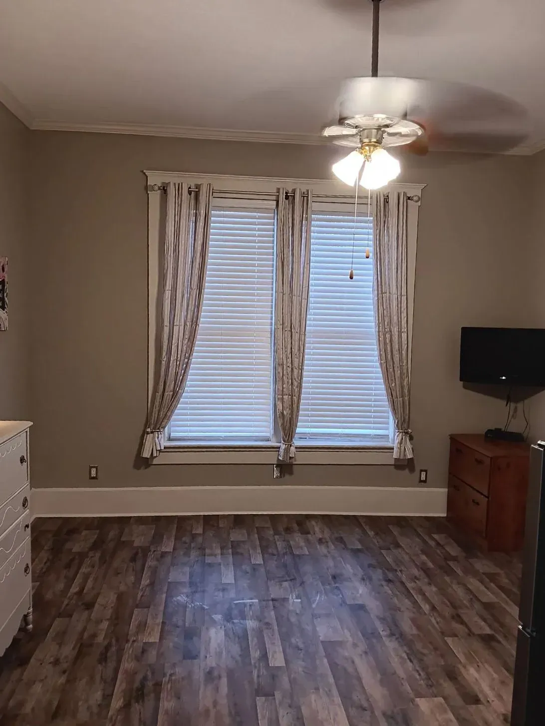 A living room with hardwood floors and a ceiling fan.