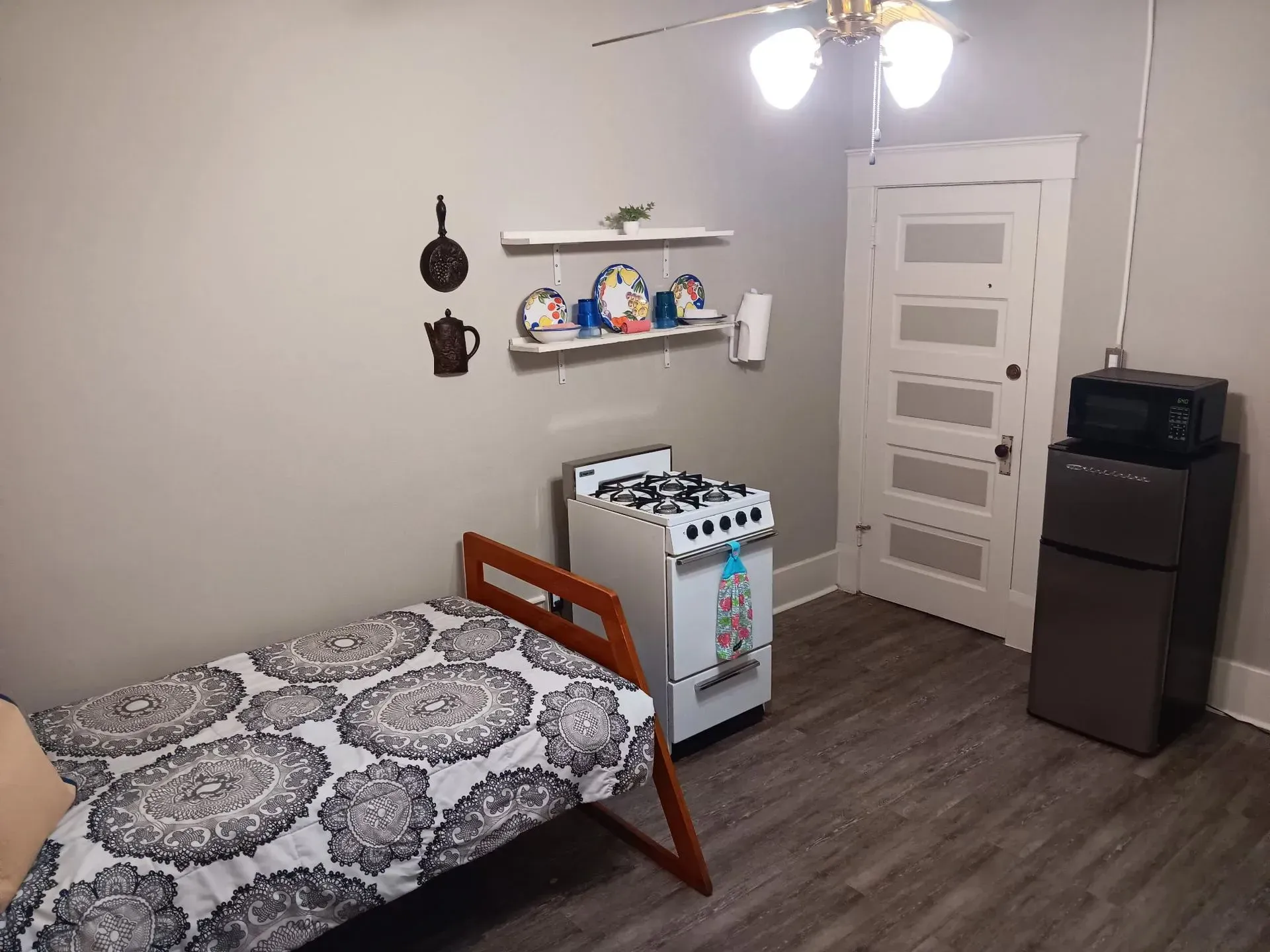A bedroom with a bed , stove , microwave and refrigerator.