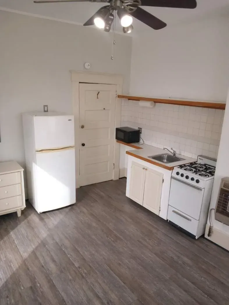 A kitchen with a refrigerator stove sink and ceiling fan