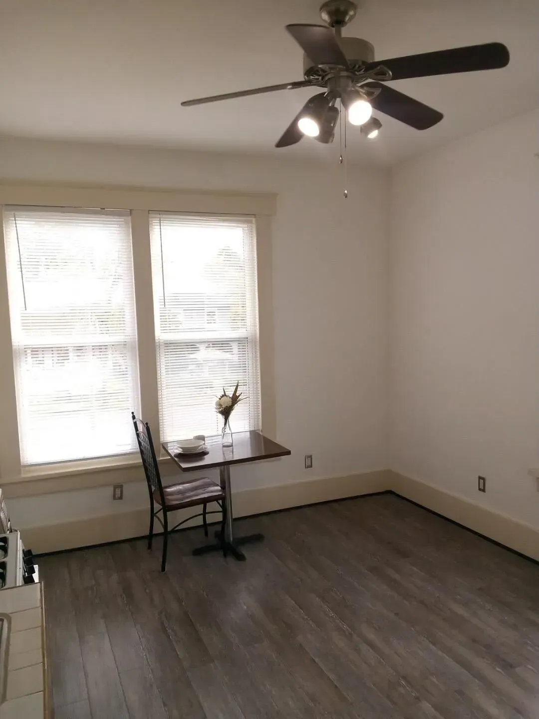 A room with a table and chairs and a ceiling fan