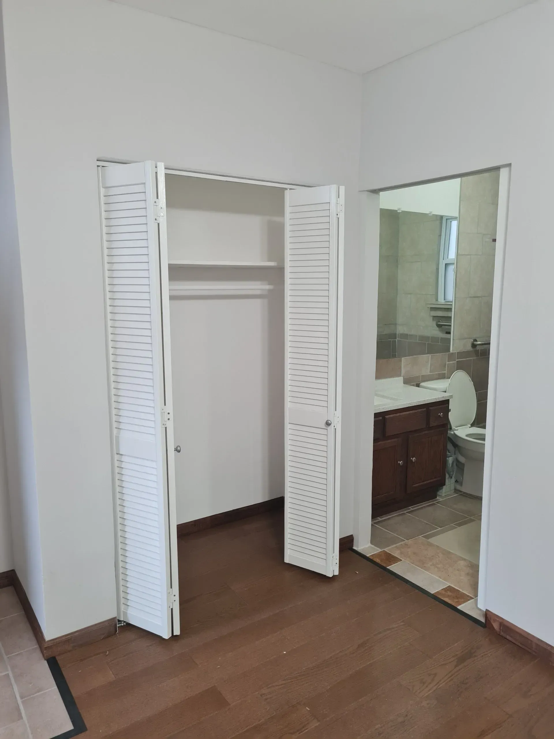An empty room with a closet and a bathroom.