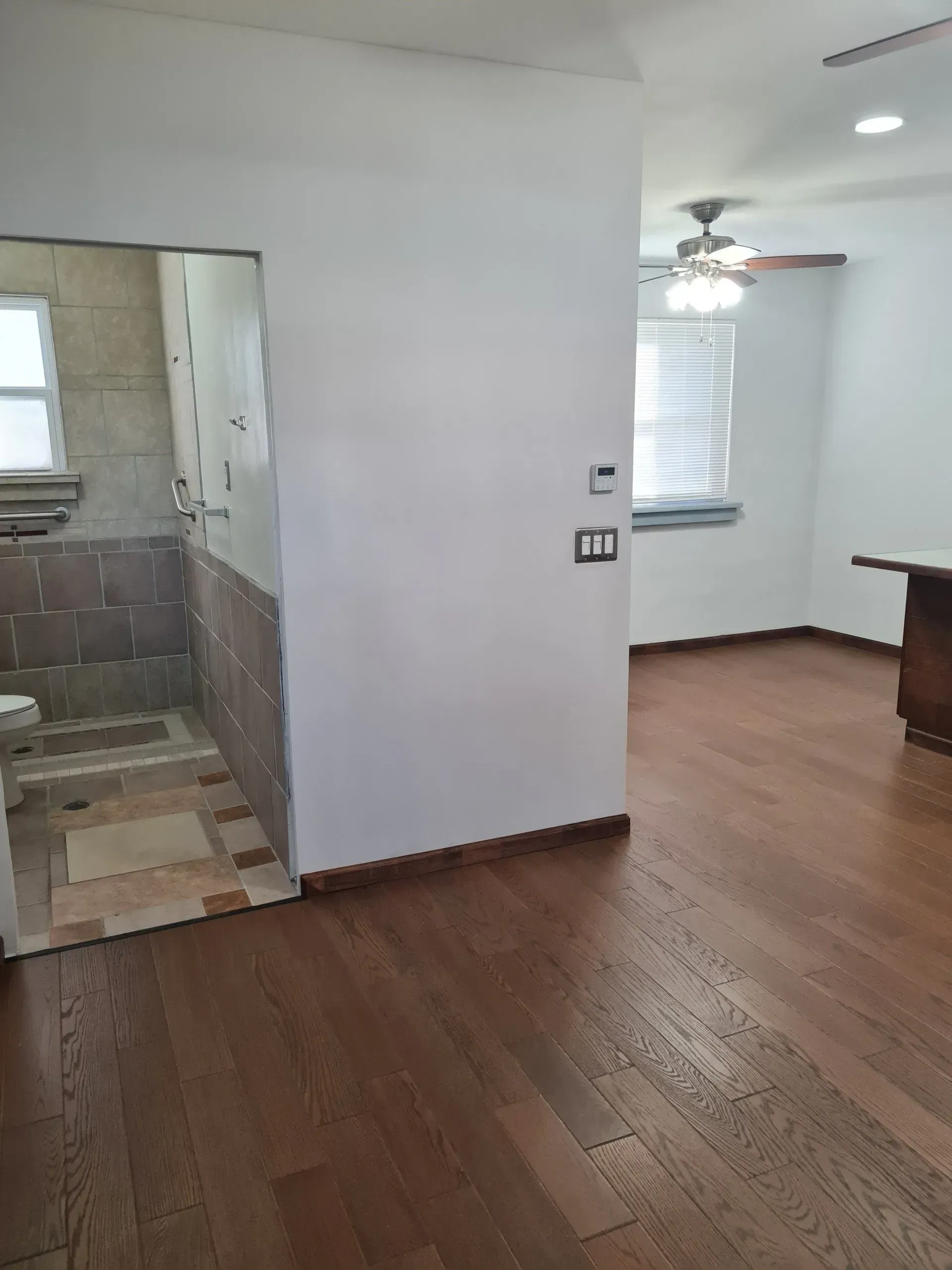 An empty room with hardwood floors and a ceiling fan.