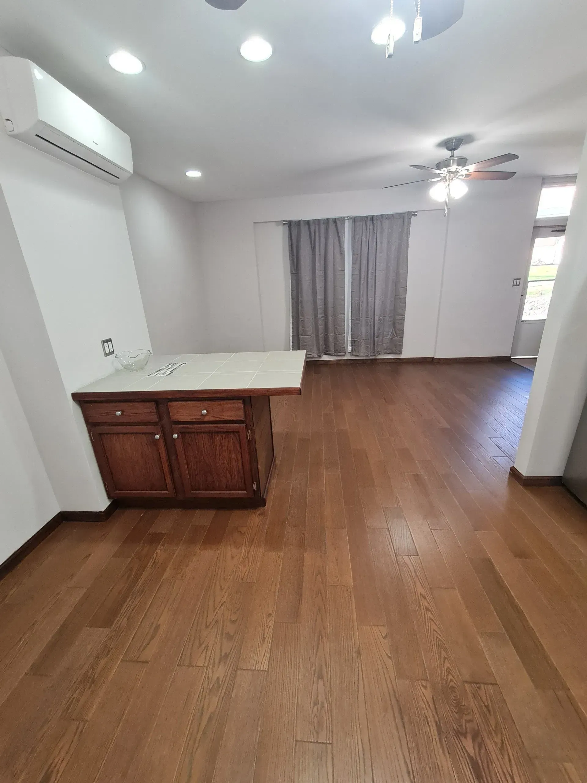 An empty room with hardwood floors and a ceiling fan.