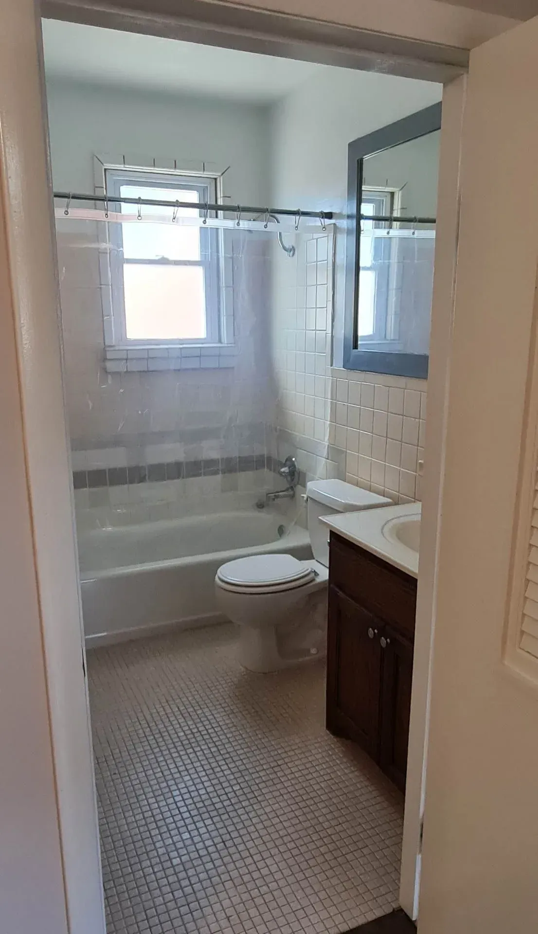 A bathroom with a toilet , sink , tub and mirror.