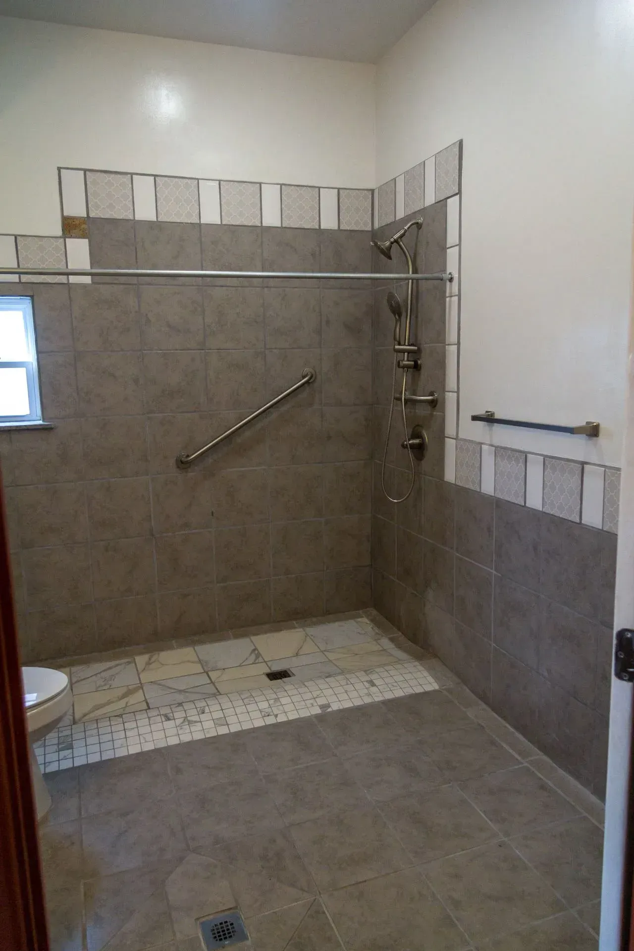 A bathroom with a walk in shower and a window.
