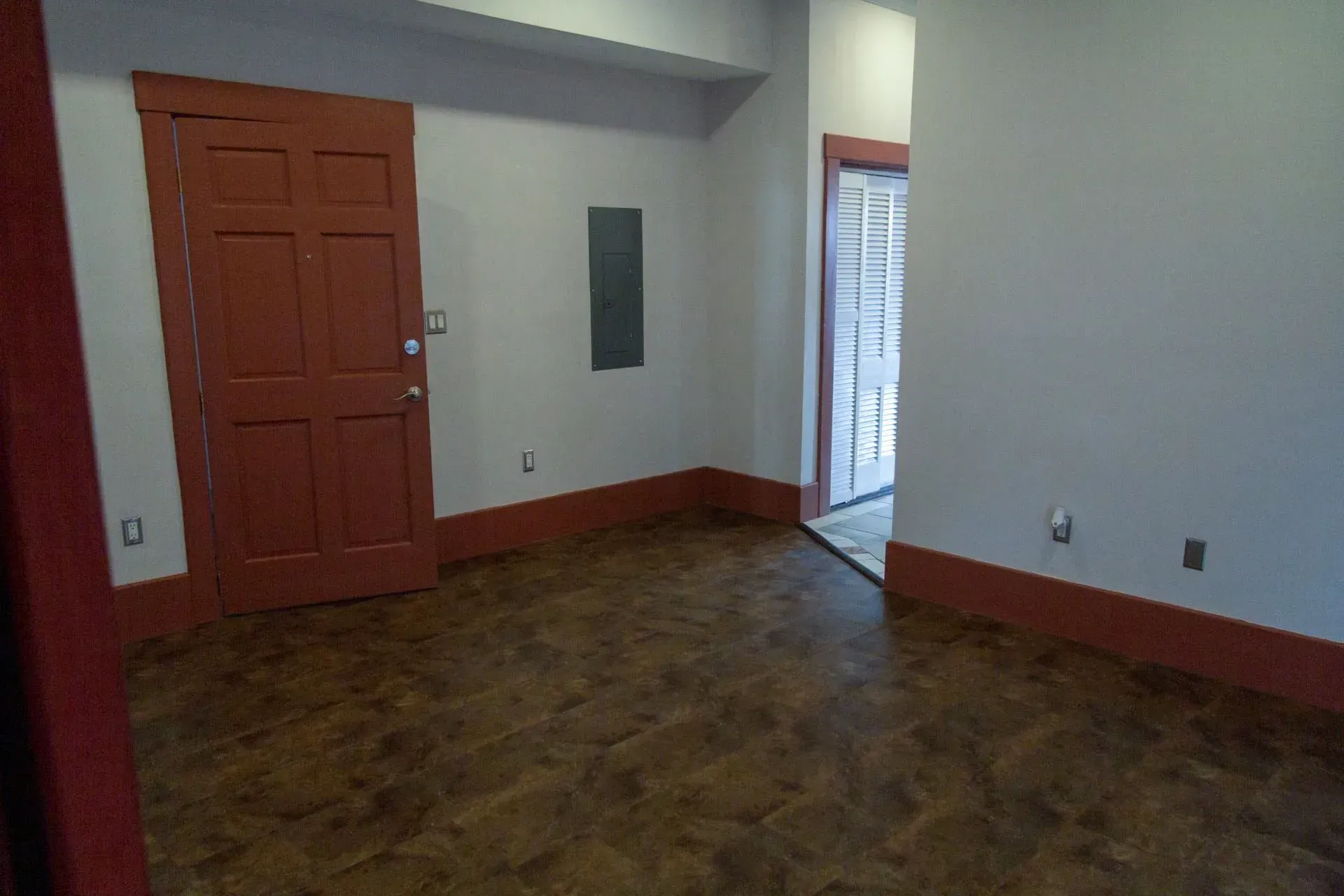 An empty room with a red door and white walls