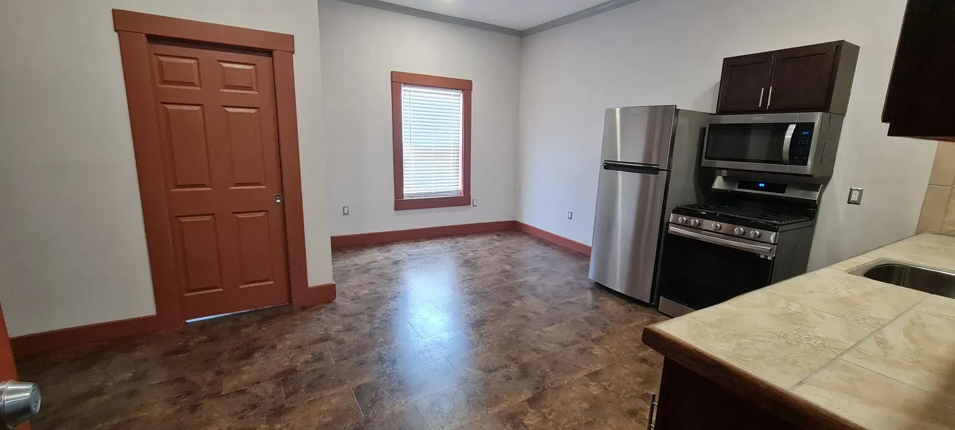 A kitchen with a refrigerator , stove , microwave and sink.