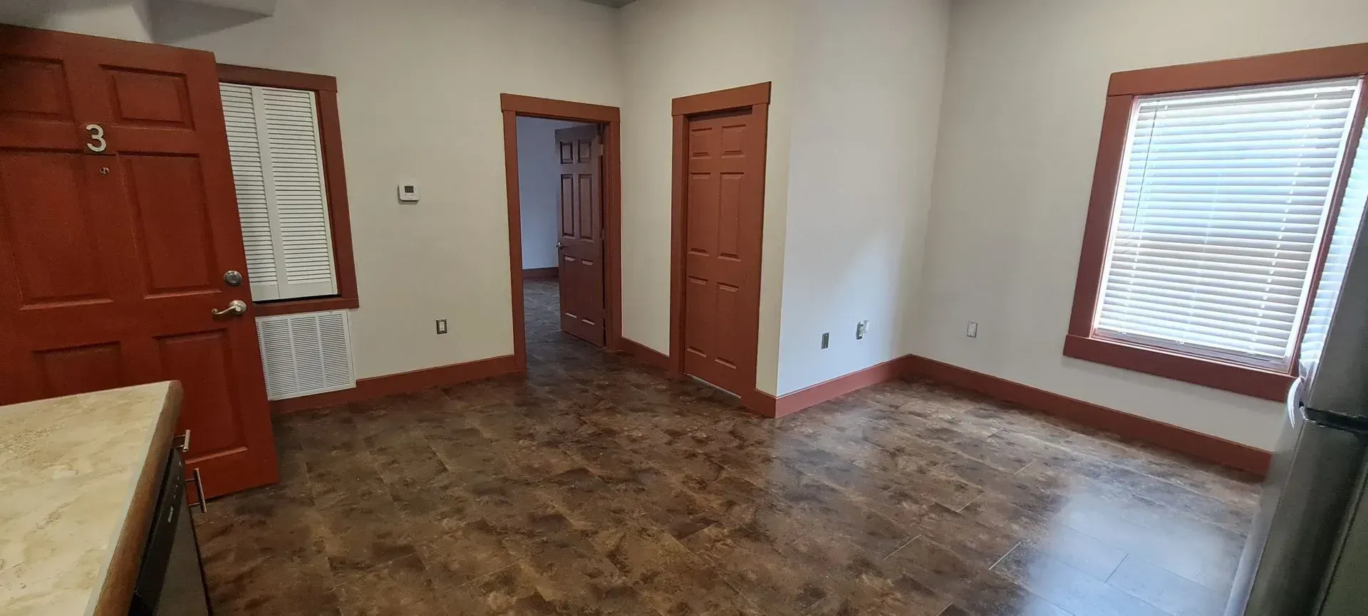 An empty room with a wooden floor and two windows.