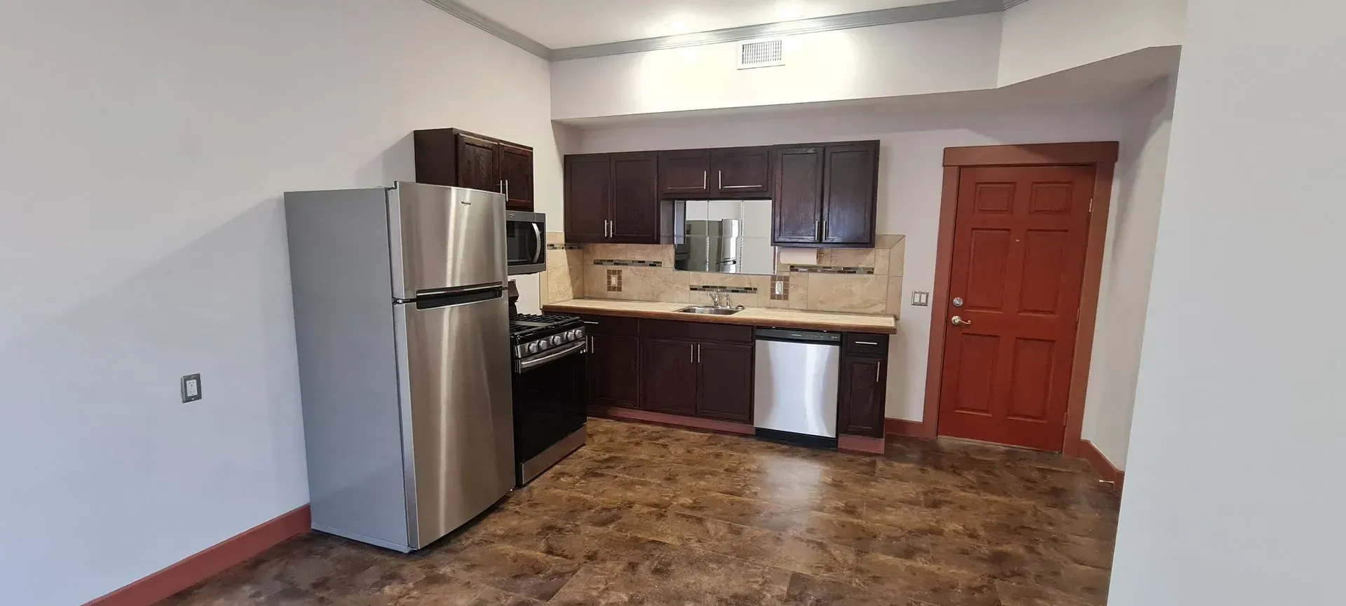 A kitchen with stainless steel appliances and a refrigerator.