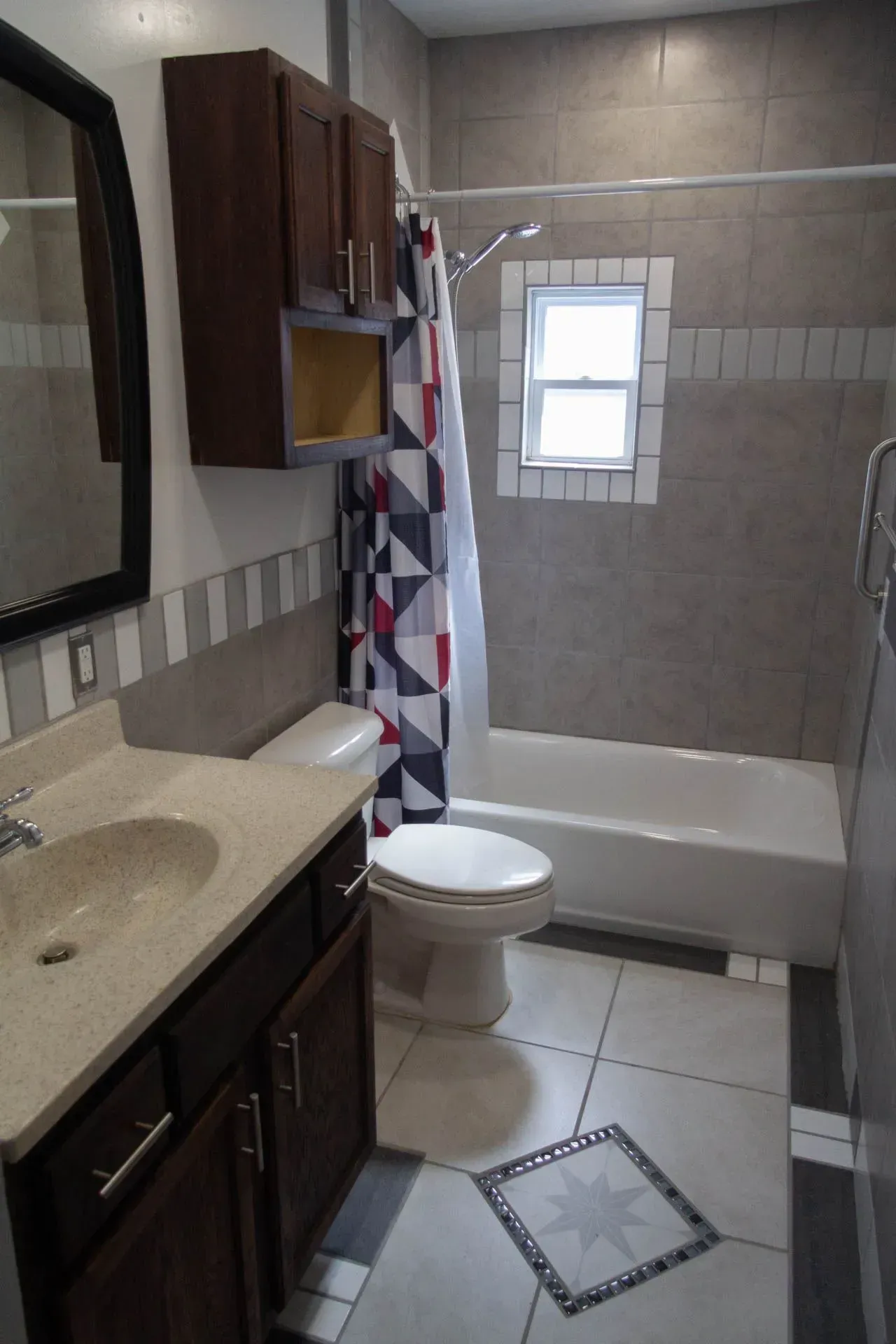 A bathroom with a toilet , sink , shower and window