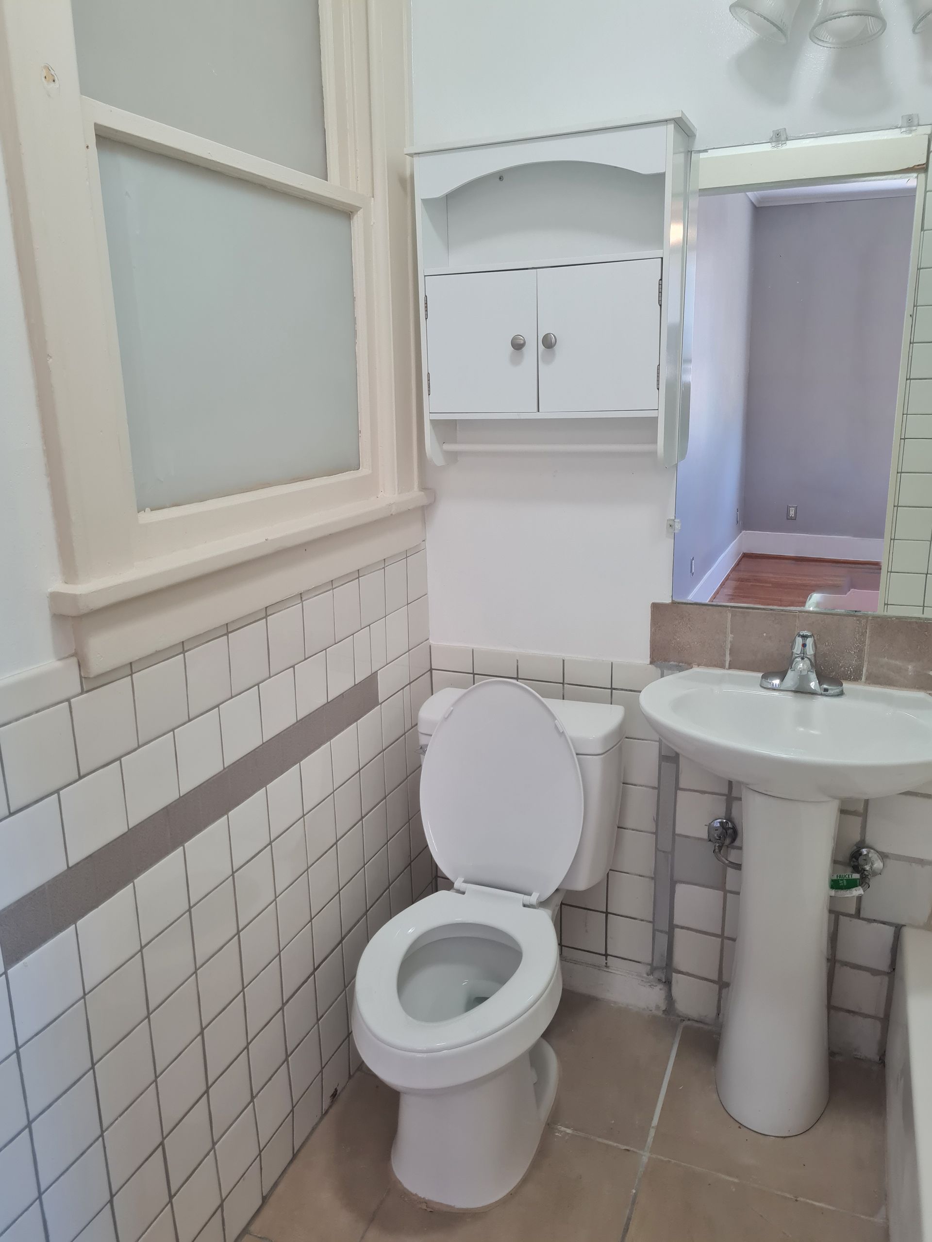 A bathroom with a toilet , sink and mirror