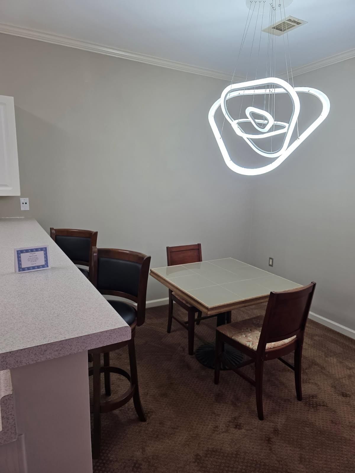 Dining area with table, chairs, countertop, and decorative light fixture.