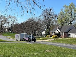 Purple pickup truck with trailer on residential street near houses.