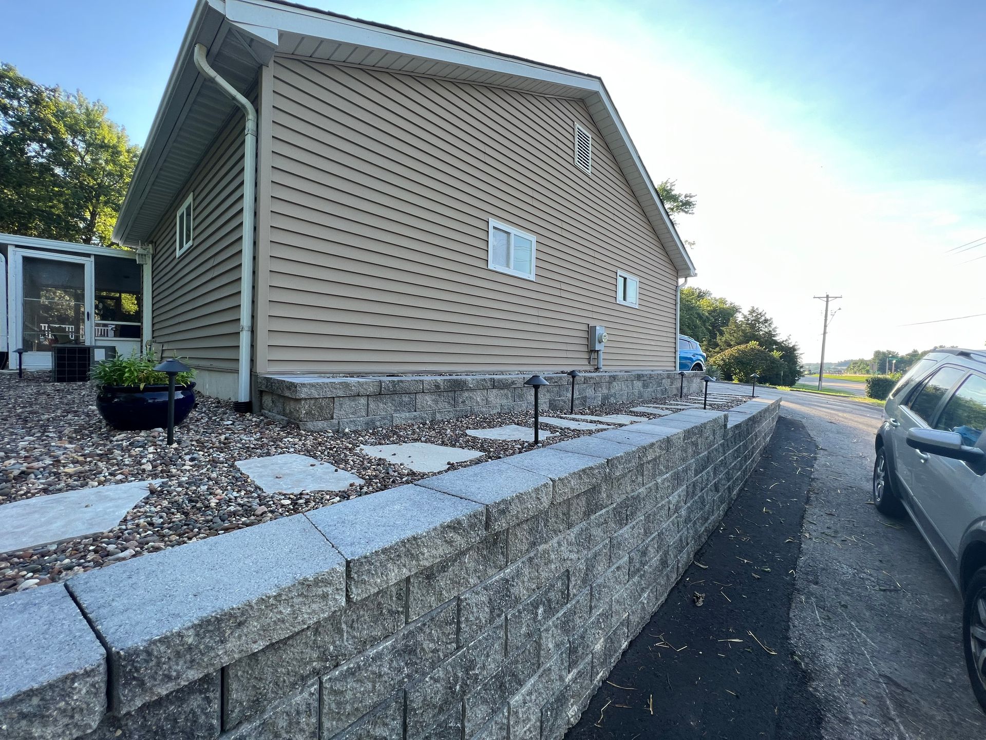 Beige house with a stone retaining wall and driveway.