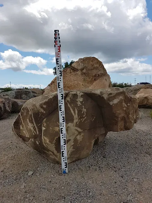 A Measuring Stick is Standing Next to a Large Rock — Blue River Landscape Supplies in Foulden, QLD