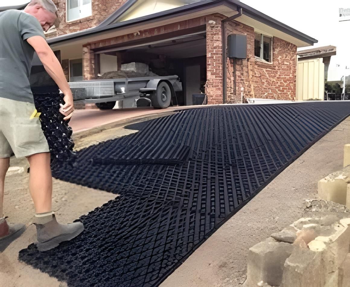 A Man is Working on a Driveway in Front of a Brick House — Blue River Landscape Supplies in Foulden, QLD