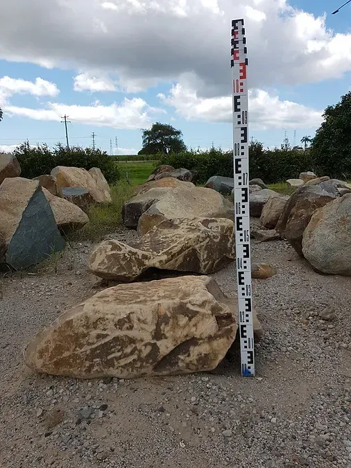 A Large Rock is Being Measured by a Long Pole — Blue River Landscape Supplies in Foulden, QLD